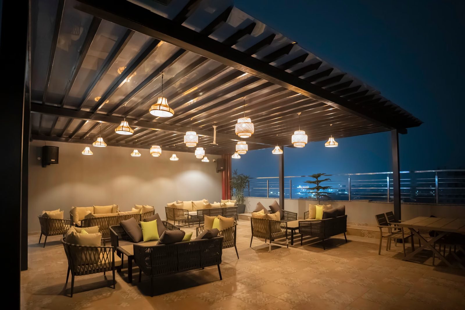 Covered rooftop terrace with lantern pendants and lounge seating at dusk