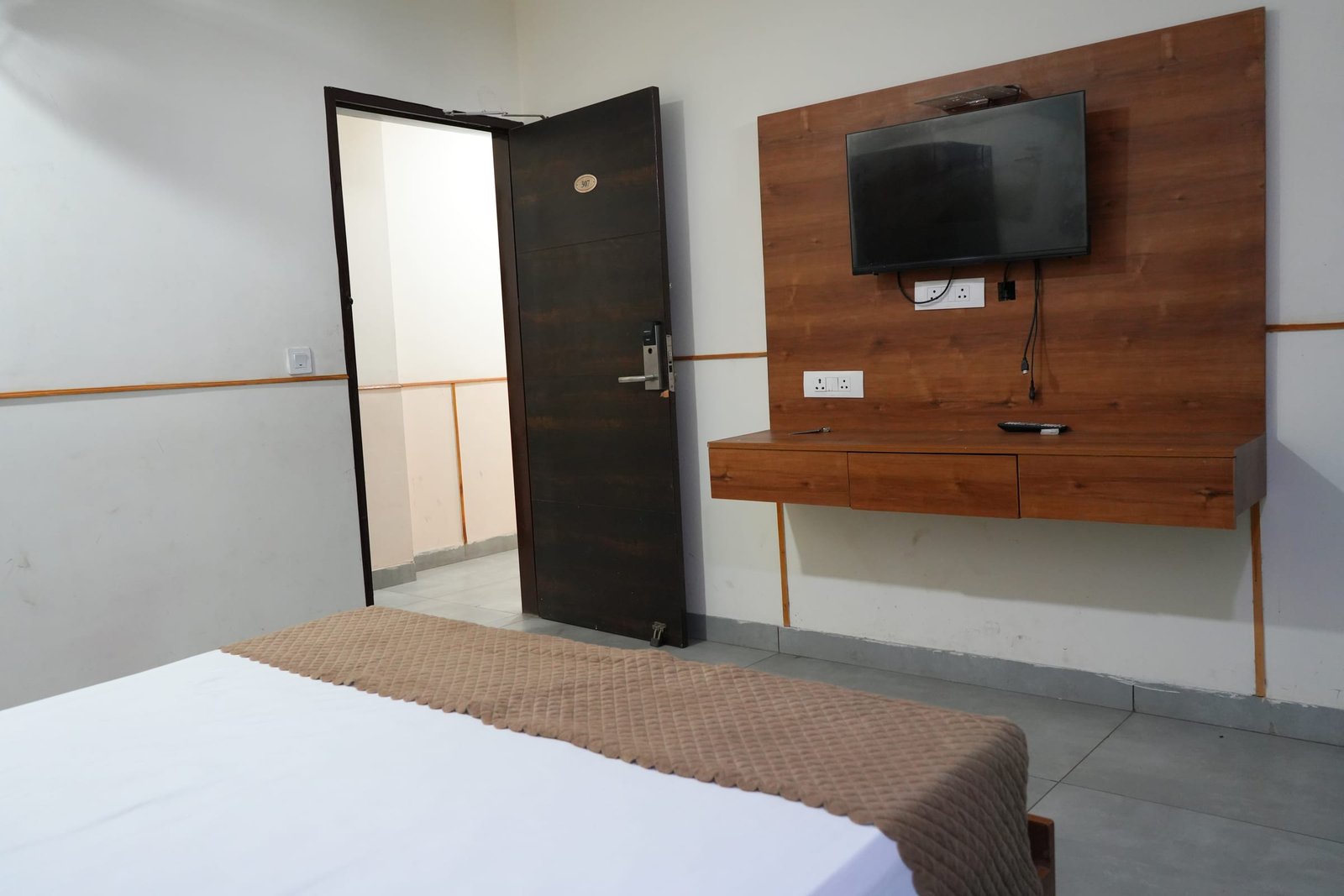 Television mounted on the wall opposite the bed