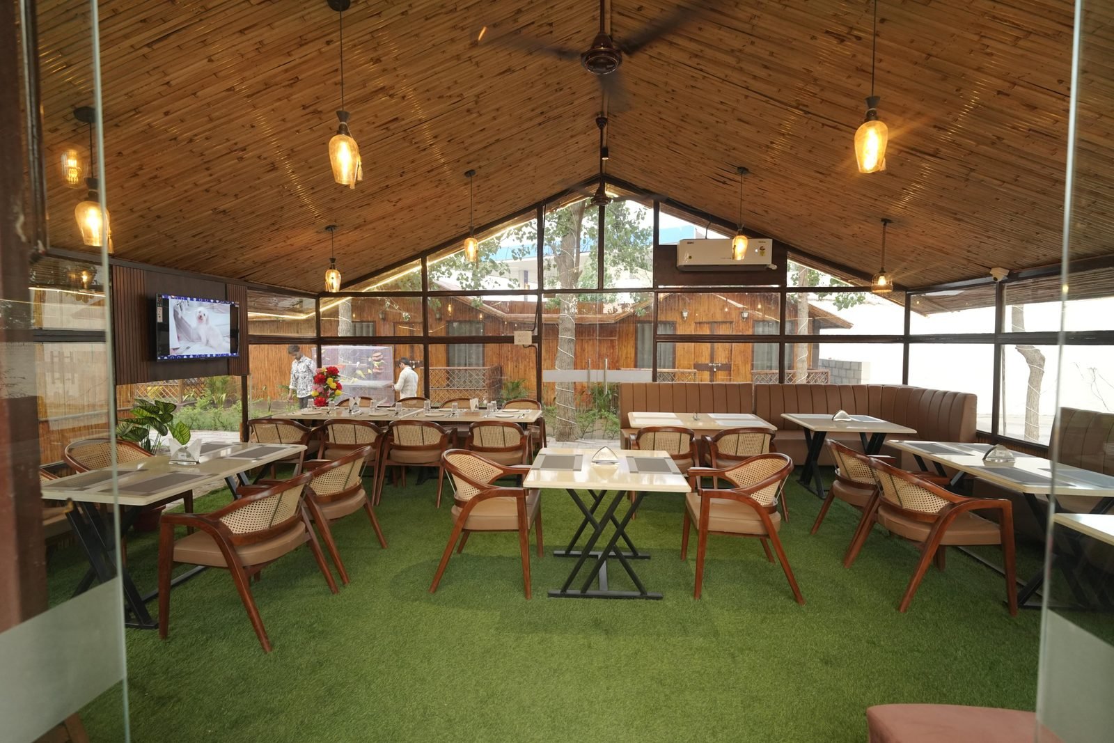 Glazed dining pavilion under a bamboo ceiling with cane chairs