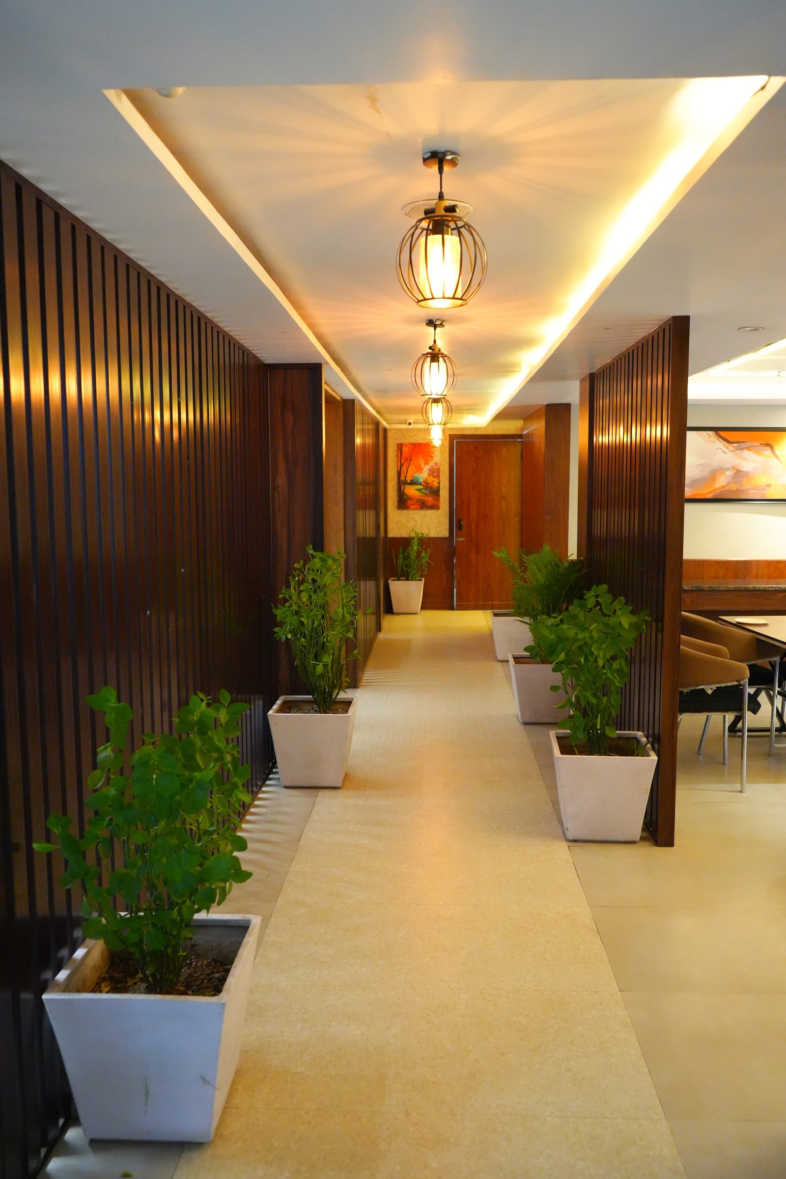 A panelled passage with potted plants and a hanging lantern